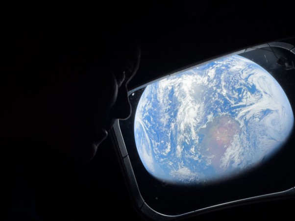 NASA astronaut and Artemis II Commander Reid Wiseman peers out of one of the Orion spacecraft’s main cabin windows, looking back at Earth, as the crew travels towards the Moon. Source: NASA